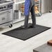 A man standing on a black Choice anti-fatigue floor mat in a kitchen.