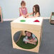 Two children playing in a wooden cube with a green light.