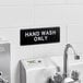 A black and white Lavex Hand Wash Only sign on a white wall with black trim.