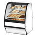 A True curved glass white dry bakery display case filled with pastries.