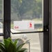 A Lavex red and white exit sign on a glass door.