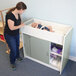 A woman using a Whitney Brothers green and white infant changing table.