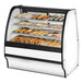 A True curved glass bakery display case with pastries inside.