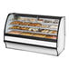 A True curved glass white dry bakery display case filled with different types of pastries.