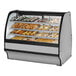 A True curved glass stainless steel bakery display case full of pastries.