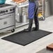 A man standing on a black Choice anti-fatigue floor mat in a kitchen.