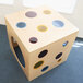 A Whitney Brothers wooden cube with colorful circles on top and portholes in the sides.