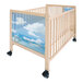 A Whitney Brothers wooden mobile crib with a glass panel and a picture of blue sky and clouds.