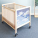 A wooden Whitney Brothers infant crib with a sky and clouds on it.