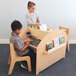 A boy and girl sitting at a Whitney Brothers wood library desk with books.