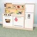 A Whitney Brothers wooden toy kitchen with white cabinets and appliances including a refrigerator with a silver handle.