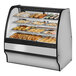 A True curved glass dry bakery display case with various types of pastries inside.