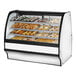 A True curved glass white dry bakery display case filled with various types of pastries.