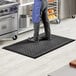 A man standing on a black Choice anti-fatigue floor mat in a kitchen.