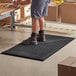 A man standing on a black Choice anti-fatigue floor mat with drainage holes.