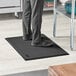 A person standing on a Lavex black anti-fatigue floor mat.