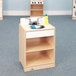 A Whitney Brothers wooden toddler sink in a playroom with a bottle on the shelf.