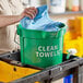 A woman holding a green Lavex bucket with clean towels.