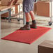 A person standing on a red Choice anti-fatigue floor mat.