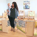 A woman using a Whitney Brothers wood divider gate to keep a baby in a playpen.