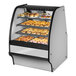 A True curved glass stainless steel dry bakery display case filled with pastries.
