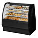 A True black curved glass dry bakery display case with various pastries inside.