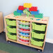 A Whitney Brothers mobile wood storage cabinet with colorful toy bins.