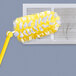 A yellow Swiffer duster with white fluffy duster cloths on the end.