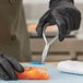 A person in black gloves using Triangle fishbone pliers to cut a piece of salmon.