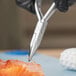 A person cutting a piece of fish with Triangle fishbone pliers.