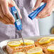A blue digital pocket probe thermometer being used to check the temperature of cooked salmon with lemon slices.