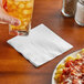 A hand holding a glass of orange liquid with ice cubes over a plate of food.