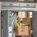 A man wearing a safety vest holding a Boltic Stainless Steel Air Curtain box in front of a door.