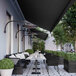 A Bromic Heating wall-mount pole on a restaurant patio table with plates and glasses.