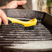 A person cleaning a pan with a Lodge Corner / Groove Scrub Brush.