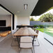 A Bromic Heating white outdoor patio heater above a wooden table and metal chairs.