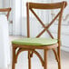 A Lancaster Table & Seating wooden chair with a green cushion tied to the seat and back.