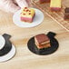 A hand holding a plate of single serve desserts on a white and black Enjay Dessert Board