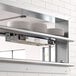 A ServIt double strip warmer mounted on a wall above a dish rack.