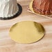 A close-up of a white and brown cake on a gold Enjay round dessert board.