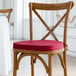 A Lancaster Table & Seating wooden chair with a merlot red cushion with ties.