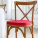 A Lancaster Table & Seating wooden chair with a red cushion tied to it.