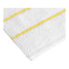 A close-up of a white Garnier-Thiebaut pool towel with yellow stripes.