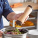 A person pouring sauce from a Vollrath Traex FIFO squeeze bottle onto a salad in a bowl.