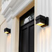 Two Globe matte black outdoor wall sconces on a white wall.