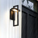 A Globe Matte Black LED Wall Sconce on a white outdoor wall.