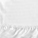 A white Garnier-Thiebaut king size fitted sheet with a ruffled edge.