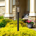 A Globe matte black LED post light on a lamp post outside a house.