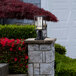 A Globe matte black LED post mount light on a stone pillar in the rain.