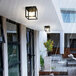 A Globe matte black outdoor ceiling light with a cubed metal cage and glass panes over a patio table.